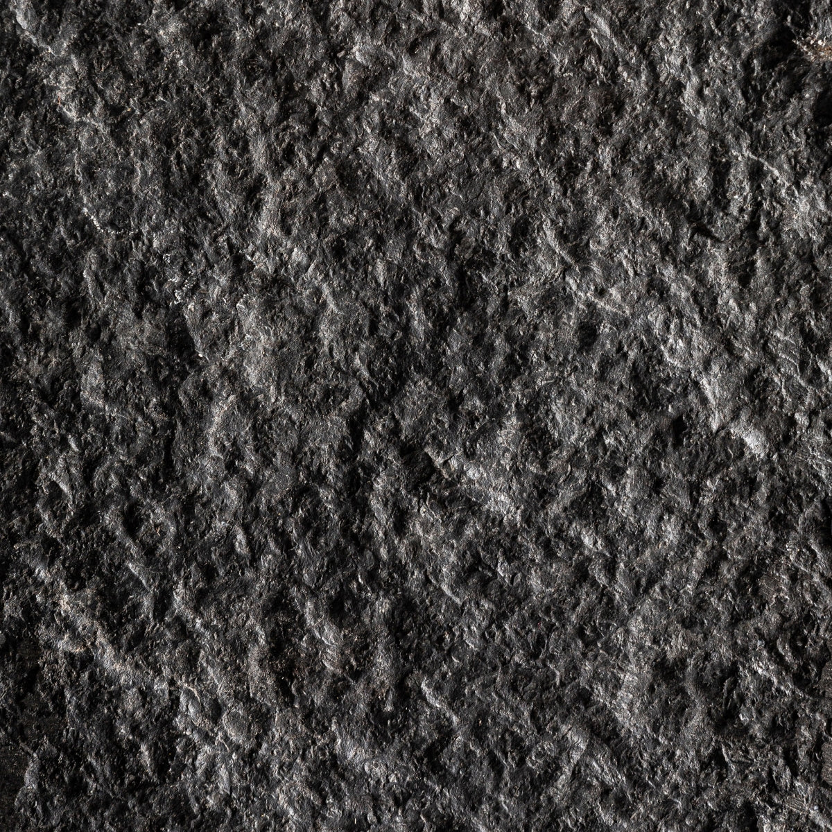 Primer plano de la figura decorativa en hierro y piedra Stone S, que muestra su textura rugosa, gris oscuro con patrones desiguales y sutiles variaciones de color, evocando el aspecto de la piedra y el hierro tradicionales utilizados en la escultura decorativa.