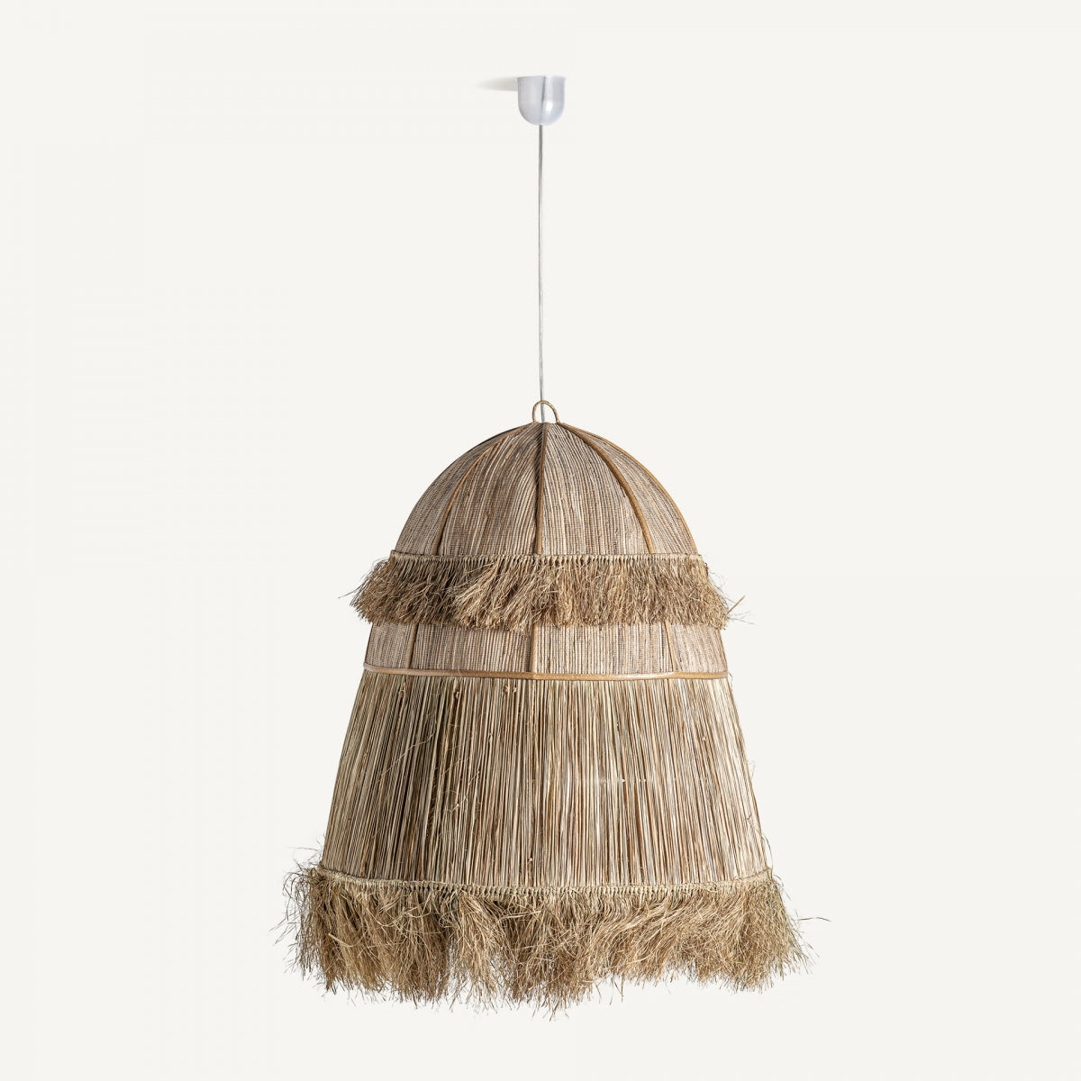 La lámpara colgante de coco en fibras Boho es una gran lámpara en forma de cúpula que presenta un diseño de ratán tejido natural con dos niveles con flecos, una bombilla central y encanto bohemio, elegantemente suspendida de un soporte de techo blanco.