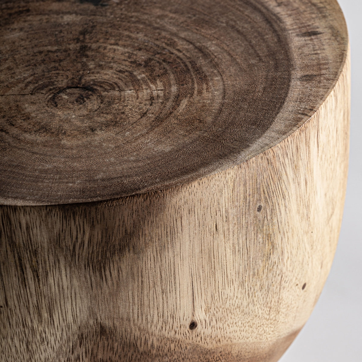 Primer plano de un asiento redondo de madera elaborado con elegante madera de suar, que muestra patrones de vetas visibles y un acabado suave, que encarna el diseño atemporal de la Mesa auxiliar en madera de suar Rimini B.