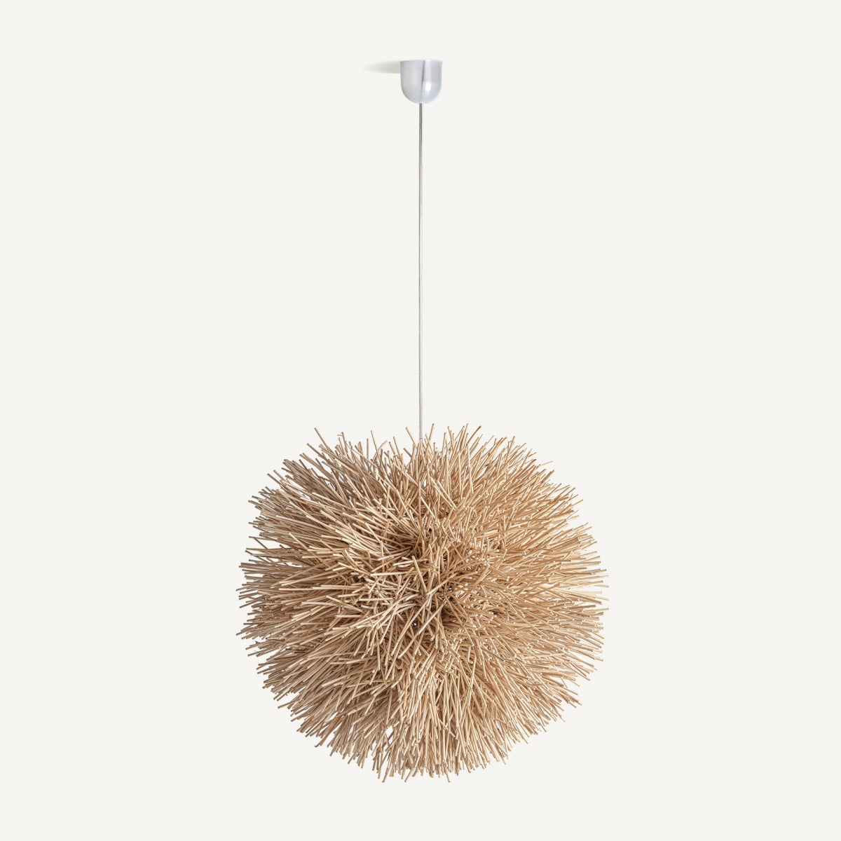 La lámpara colgante en ratán marrón Luxio, con una pantalla esférica de finas varillas de madera, se asemeja a un erizo de mar o un diente de león suspendido del techo, añadiendo encanto boho y elegancia natural a cualquier espacio.
