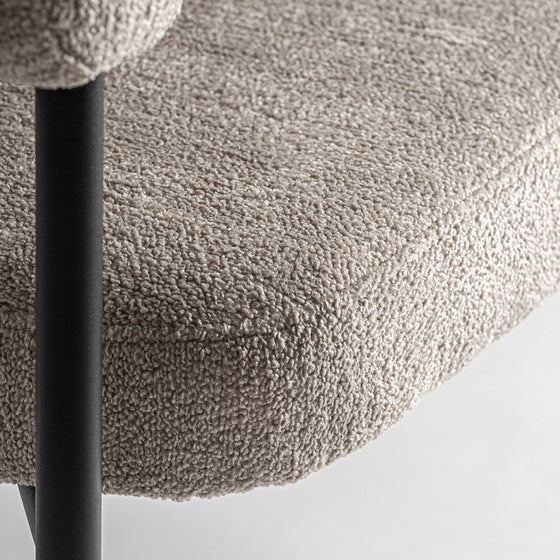 Primer plano de la silla de comedor Albula gris claro, que presenta un asiento acolchado texturizado con poliéster duradero y elegantes patas de metal negro.
