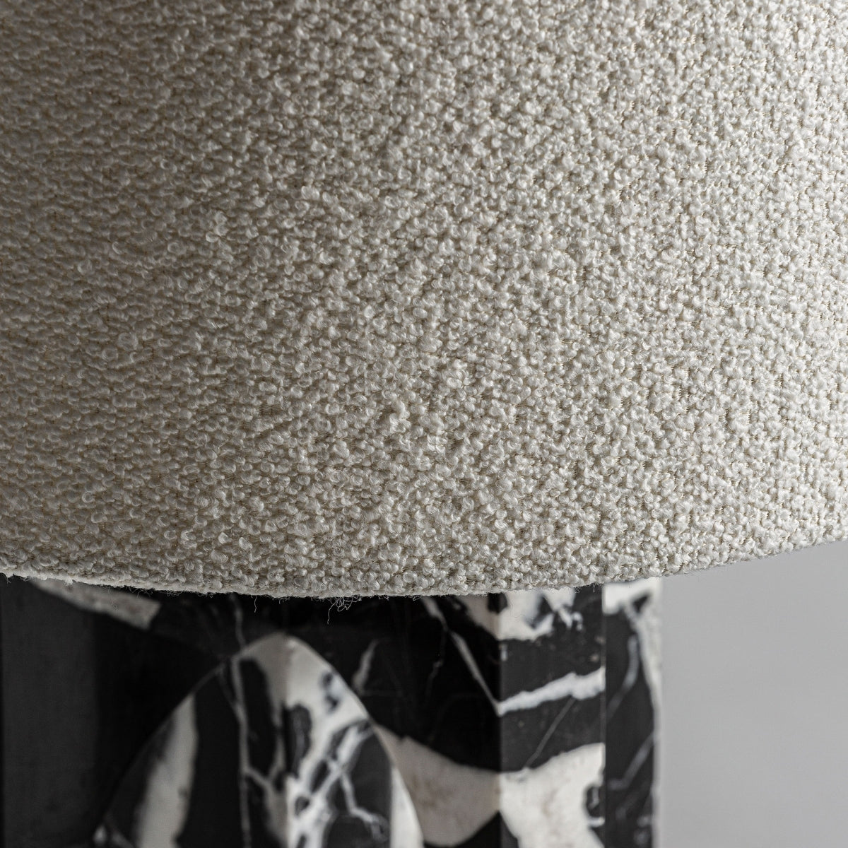 Primer plano de una pantalla texturizada de color blanquecino sobre la elegante Lámpara de sobremesa en mármol y bronce Arcis que presenta una llamativa base de mármol negro en un refinado diseño Art Deco.