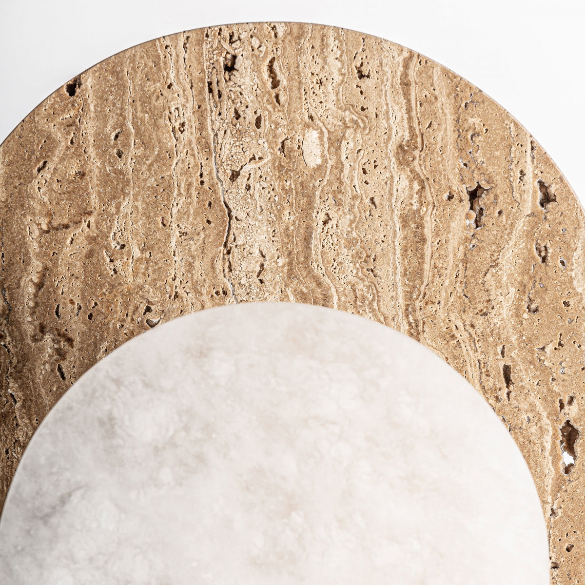 Primer plano de dos superficies circulares superpuestas, una marrón texturizada y otra blanca lisa, que evocan el refinado estilo art déco de la Lámpara de mesa en mármol y bronce Nobra, sobre un fondo blanco.