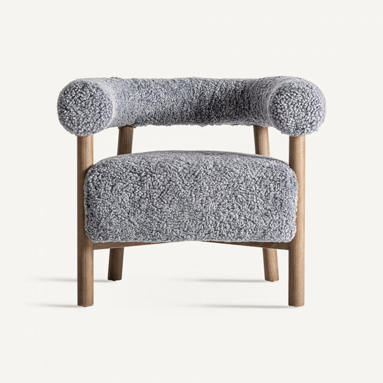 El sillón tapizado y madera de fresno Allitz es una silla moderna con patas de madera y tela gris texturizada redondeada en el asiento y el respaldo, que ejemplifica el diseño contemporáneo al tiempo que proporciona una comodidad excepcional sobre un fondo liso.