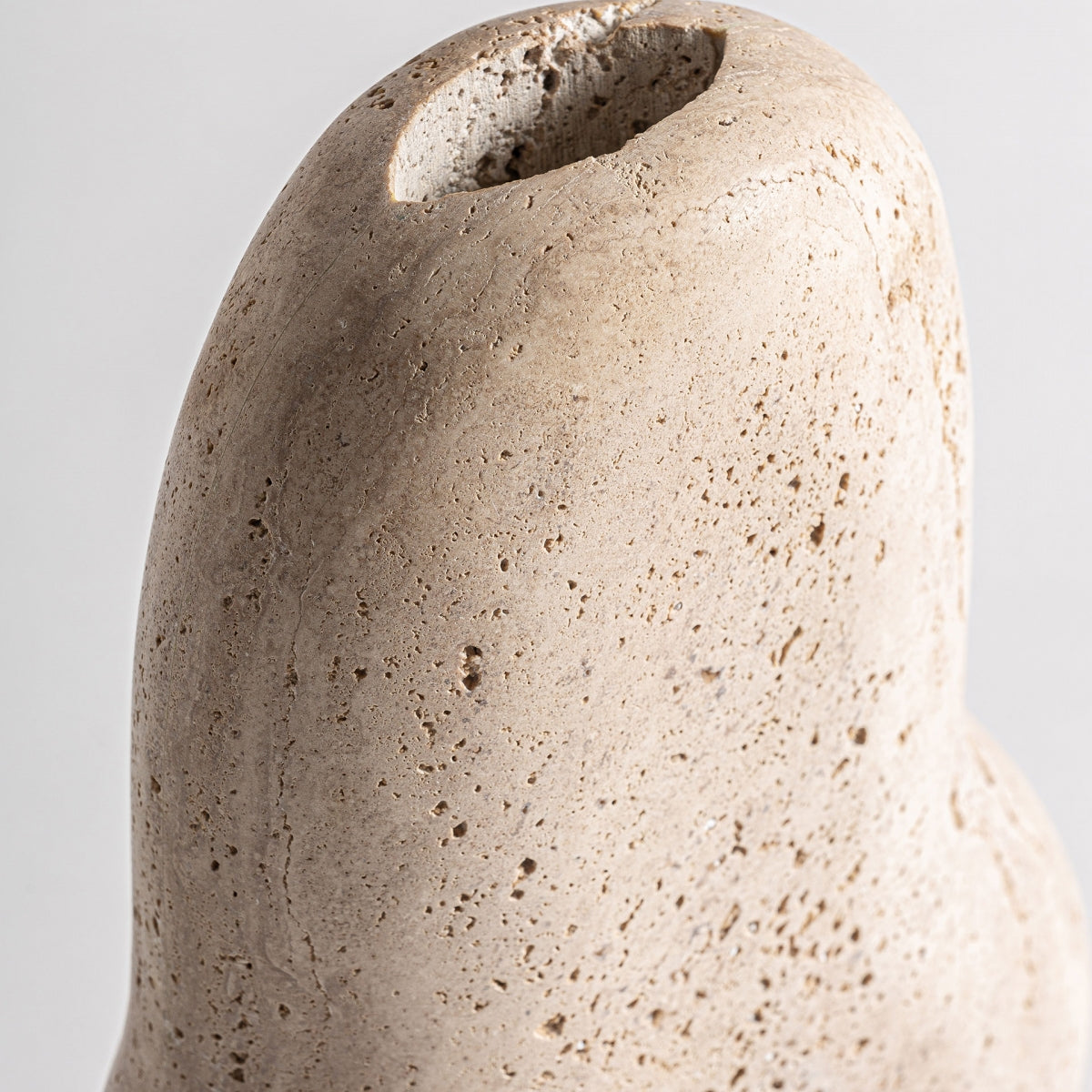 Primer plano del jarrón contemporáneo en mármol crema Jasha, con una superficie lisa de color beige, forma redondeada y tapa ahuecada, que evoca una elegancia atemporal en el diseño contemporáneo.