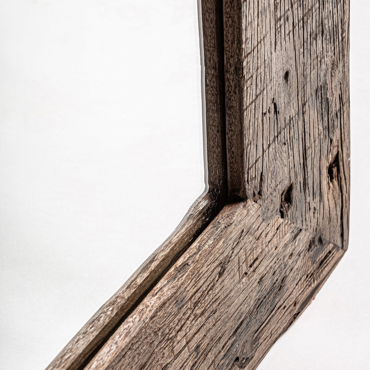 Primer plano de una esquina del Espejo colonial en madera recuperada (120x220 cm) Samsun, que muestra su veta de madera rústica, textura y nudos sobre un fondo liso para una apariencia de auténtico diseño vintage.