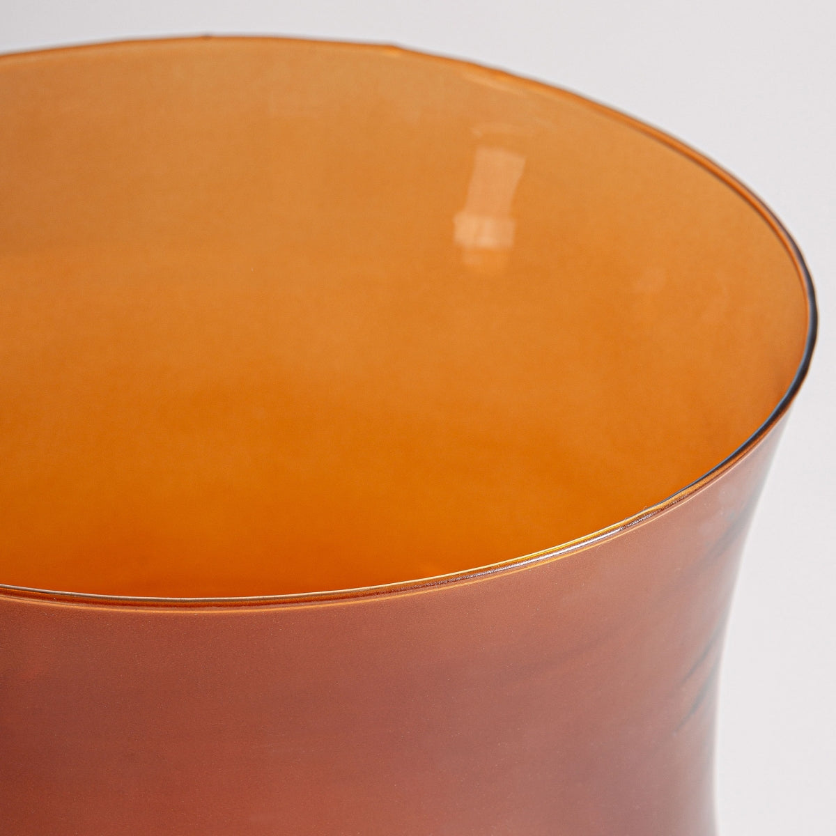 Primer plano del borde superior y el interior de un Jarrón en vidrio naranja Covasna de color naranja translúcido sobre un fondo liso y claro, ideal para decoración moderna.