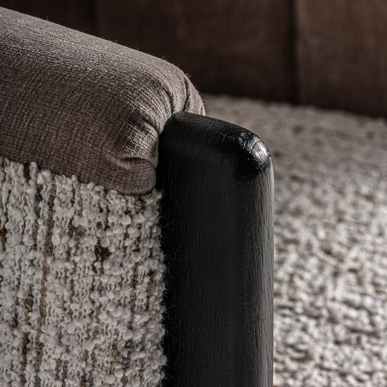 Primer plano de un Sillón tapizado jaspeado Erbach TN - Madera de pino mostrando su diseño contemporáneo, cojín jaspeado texturizado, marco de madera de pino y alfombra tejida que resaltan su elegancia y comodidad.