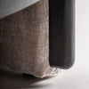 Primer plano de la esquina inferior de un Sillón tapizado jaspeado Erbach TN - Madera de pino; algunas telas aparecen deshilachadas y ligeramente rasgadas, contrastando sutilmente con su elegante y cómodo diseño contemporáneo.