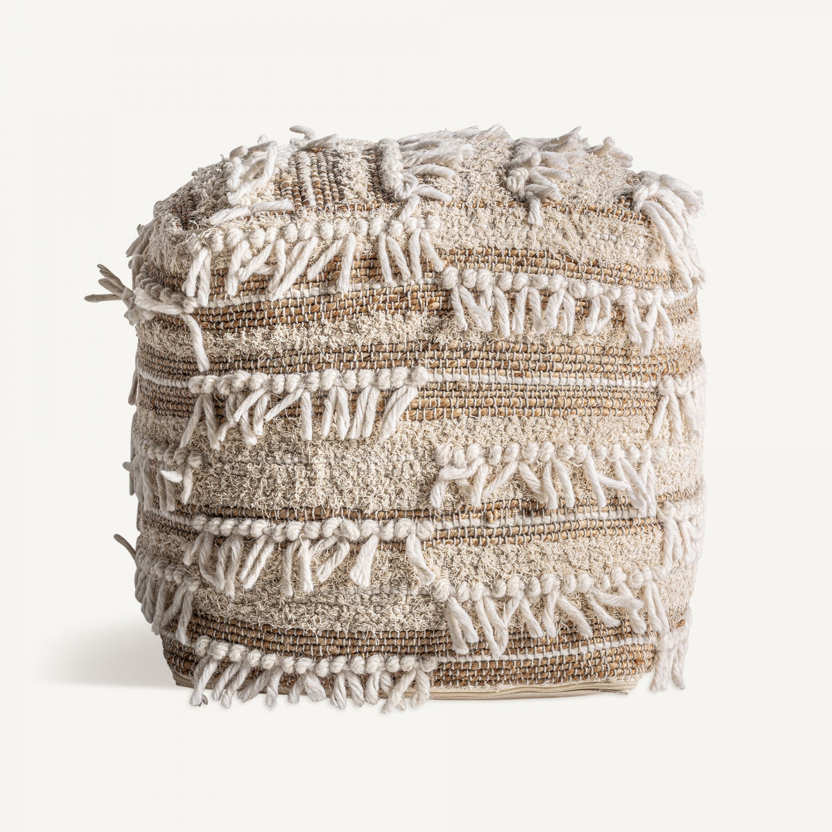 El Puff cuadrado de yute y algodón Zuri, con un diseño texturizado en beige con borlas con flecos y rayas horizontales, captura un encanto boho mientras descansa sobre un fondo blanco liso.