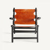 Vista frontal del Sillón en madera de mango y piel Bourthes, con asiento de cuero marrón y marco negro, resaltando su diseño simple y minimalista con estilo vintage sobre un fondo blanco.
