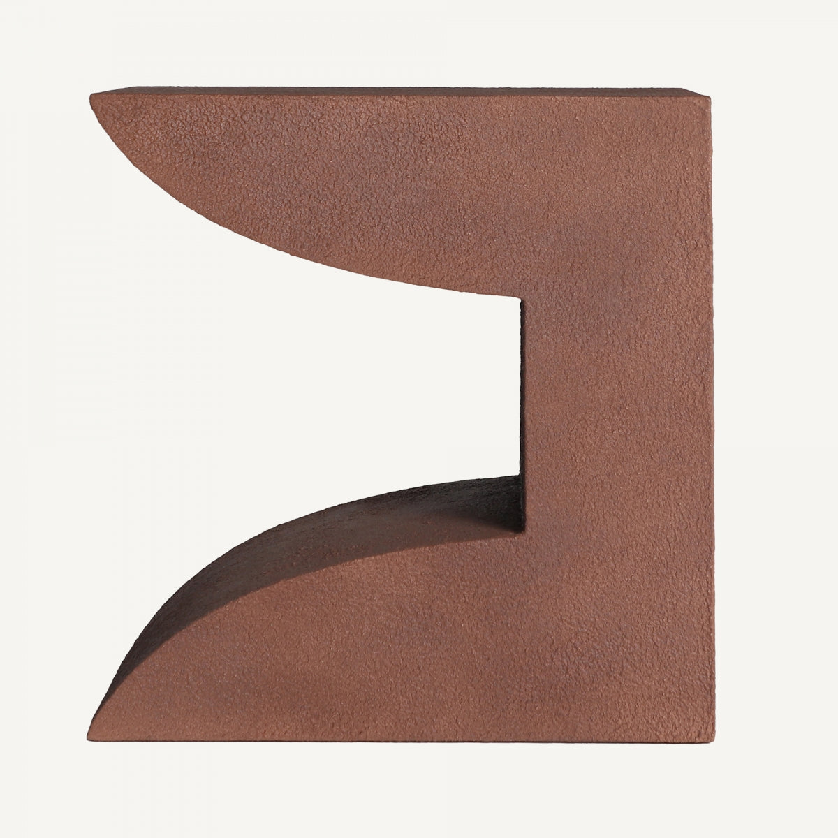 La Mesa auxiliar de cemento y madera Steinach es una pieza abstracta de color marrón, en forma de L y con bordes curvos, que se asemeja a una caja abierta o un espacio parcialmente cerrado sobre un fondo liso y que rezuma diseño contemporáneo.