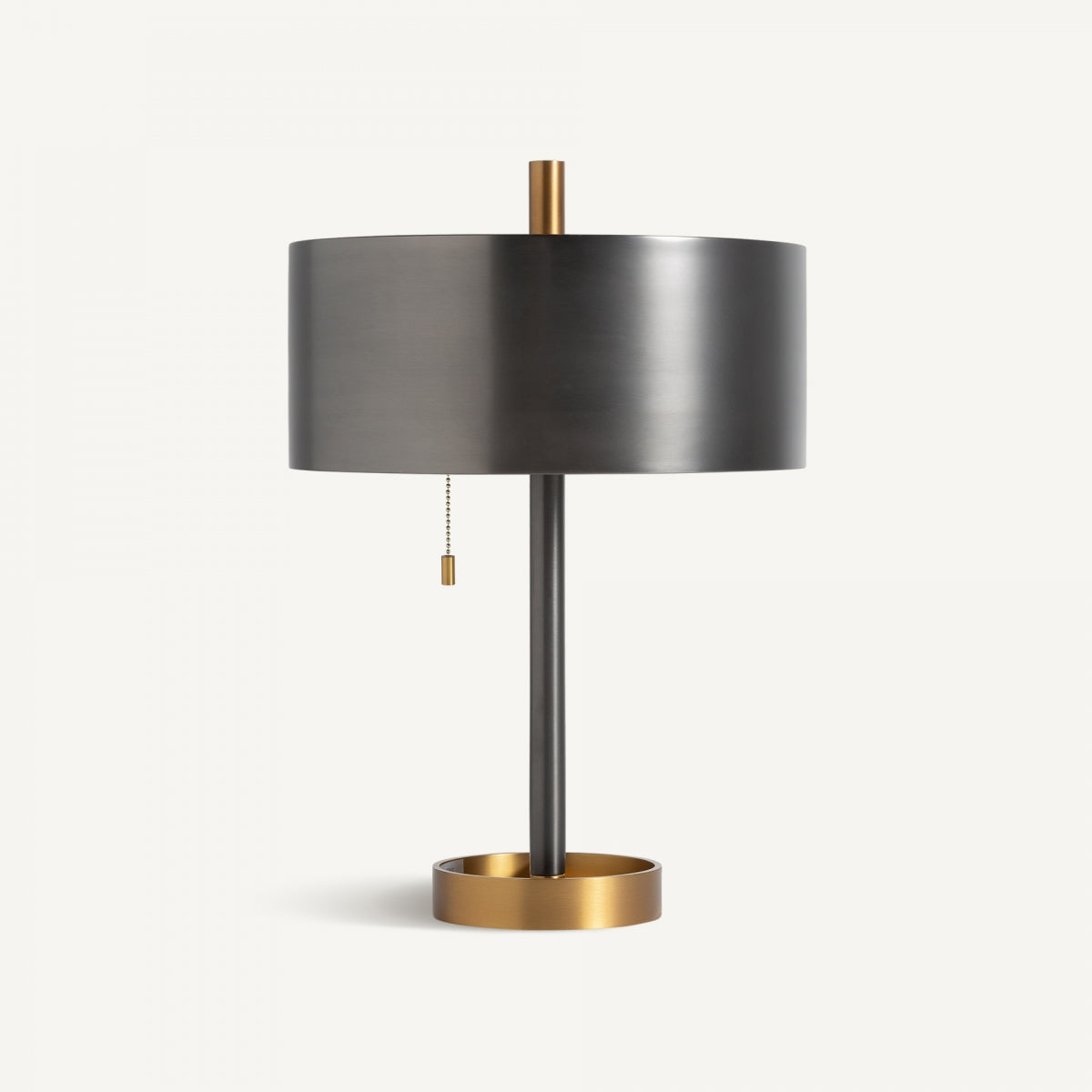 La Lámpara de sobremesa en bronce y dorado Nobia combina pantalla negra cilíndrica, base redonda dorada y pie delgado, con cadena de encendido, ideal para añadir iluminación ambiental con estilo art deco.