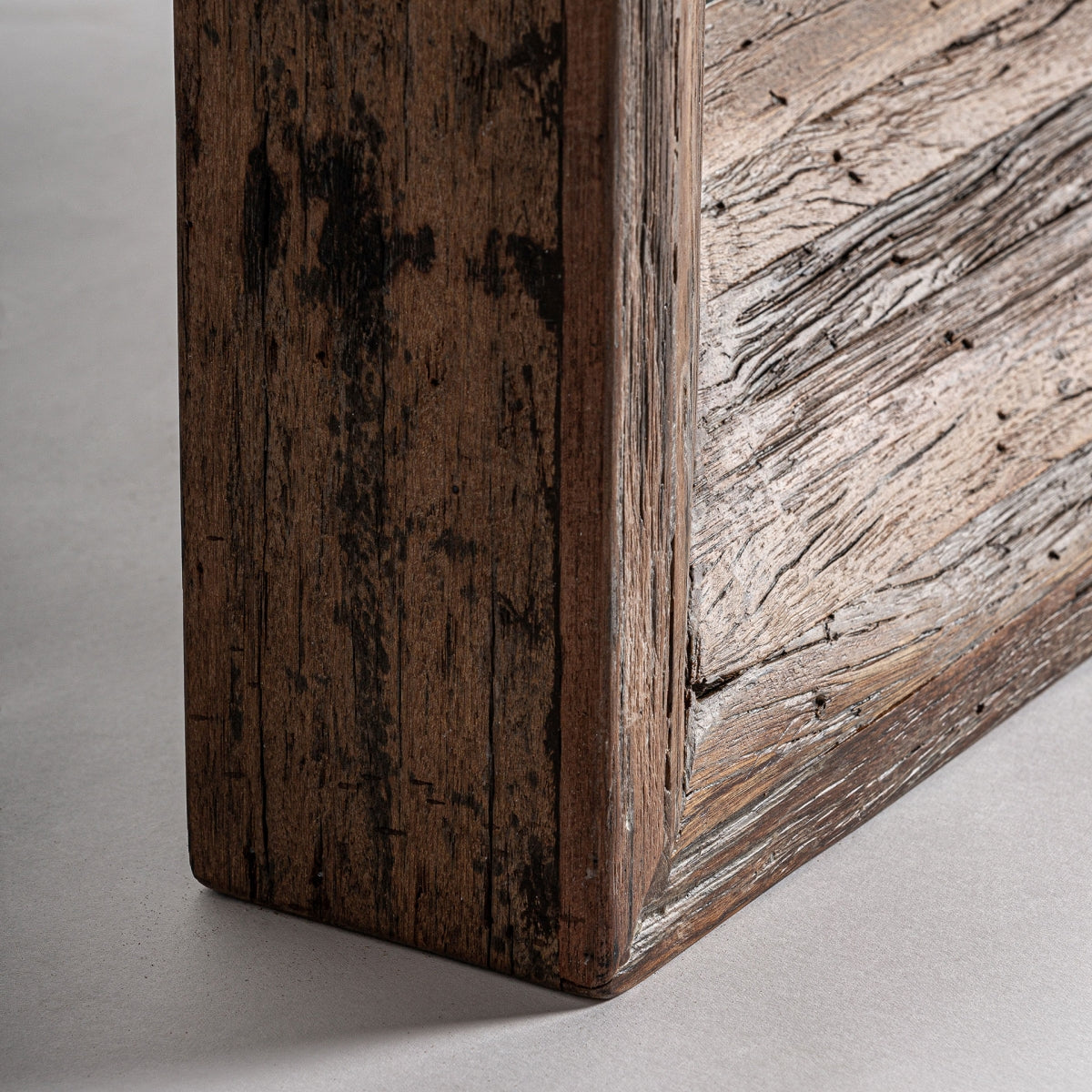 Primer plano de una junta de esquina del Espejo de pared en madera tropical Toigne (150x92 cm) sobre un fondo liso, resaltando su textura desgastada y detalles de diseño contemporáneo.