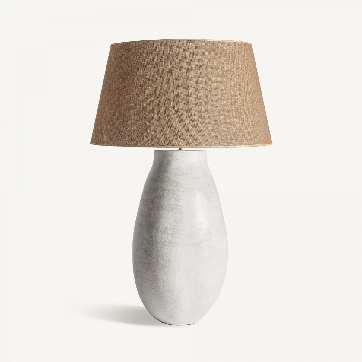 La lámpara de sobremesa Ohara combina una base de cemento con pantalla de yute beige en un diseño contemporáneo, presentada sobre fondo blanco.