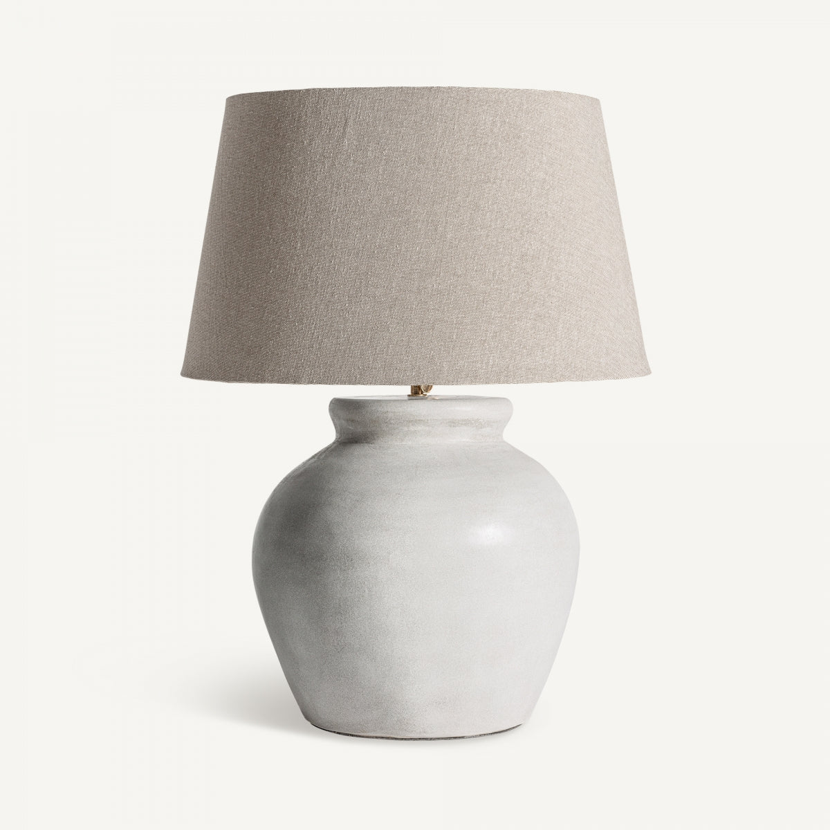 La lámpara de mesa en cemento blanco y algodón Seren destaca con su base redondeada y pantalla beige, reflejando un diseño contemporáneo sobre un fondo neutro.