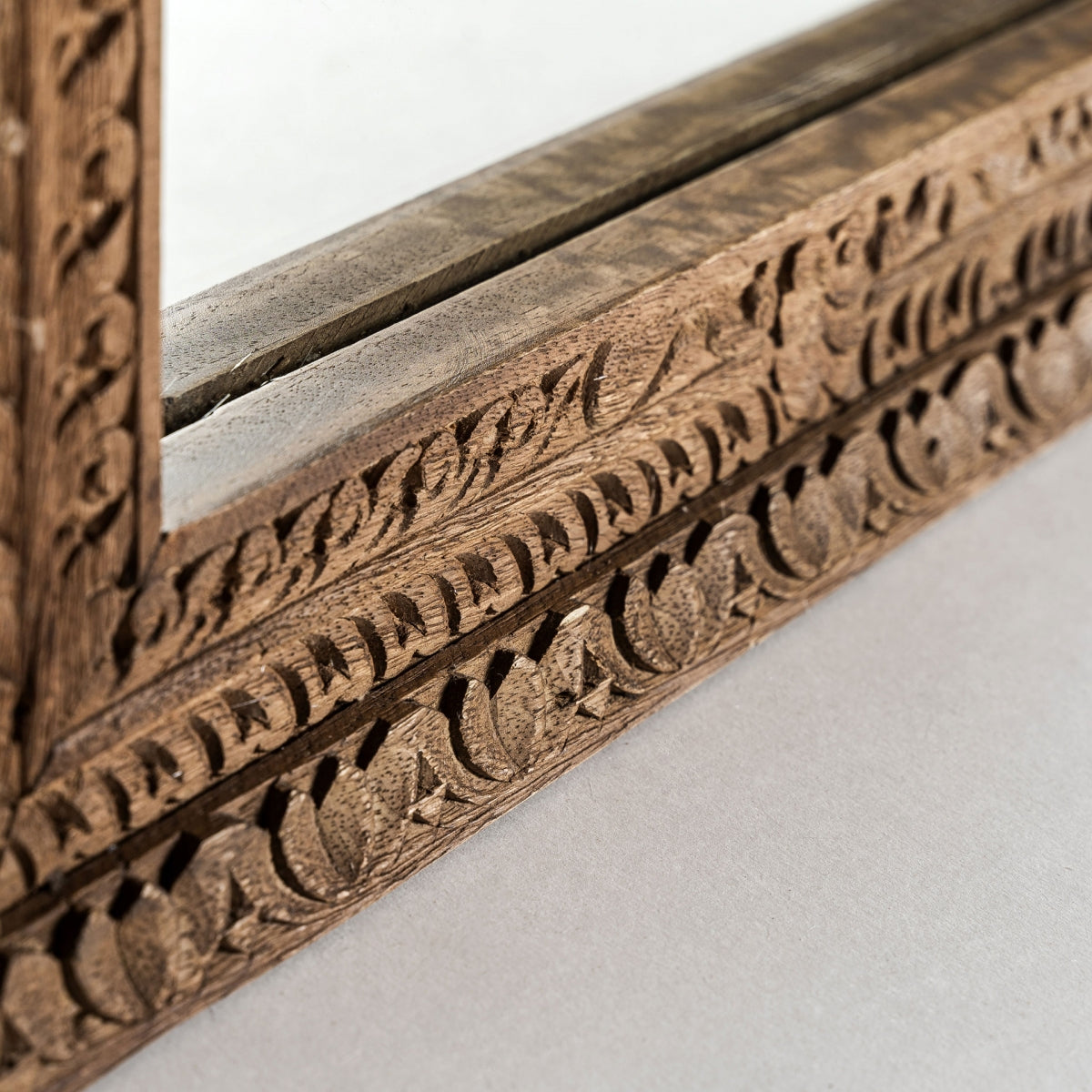 Primer plano del Espejo de pie en madera de mango (50x150 cm) Cotard, con intrincados detalles florales tallados, perfecto para la decoración interior o para darle estilo nórdico a tu espacio, con un vistazo al vidrio y la esquina sobre una superficie lisa.
