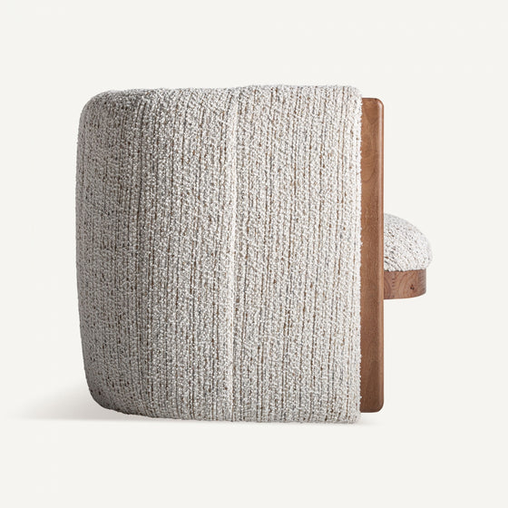 Un sillón tapizado en jaspeado Erbach - Madera de pino en color beige claro, con tapizado texturizado y un panel lateral de madera de pino, se muestra de lado sobre un fondo liso.