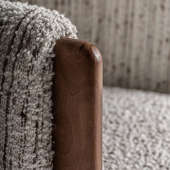 Primer plano de un apoyabrazos de madera de pino con una manta de punto texturizada en gris claro, resaltando el diseño art déco contemporáneo del Sillón tapizado en jaspeado Erbach en el fondo tapizado a juego.