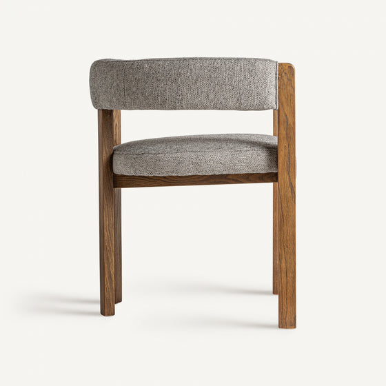 Vista frontal de la Silla de comedor en madera de fresno Wizerne, que muestra un marco de madera con un asiento y respaldo tapizados en gris, resaltando su sutil diseño rústico sobre un fondo liso.