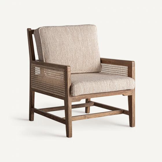 Elegancia clásica define el Sillón en madera de mango y mimbre Romarand, un sillón de madera con respaldo y lados de mimbre tejido. Incluye unos cojines de rayas beige que destacan sobre un fondo blanco liso, ejemplificando un estilo atemporal.