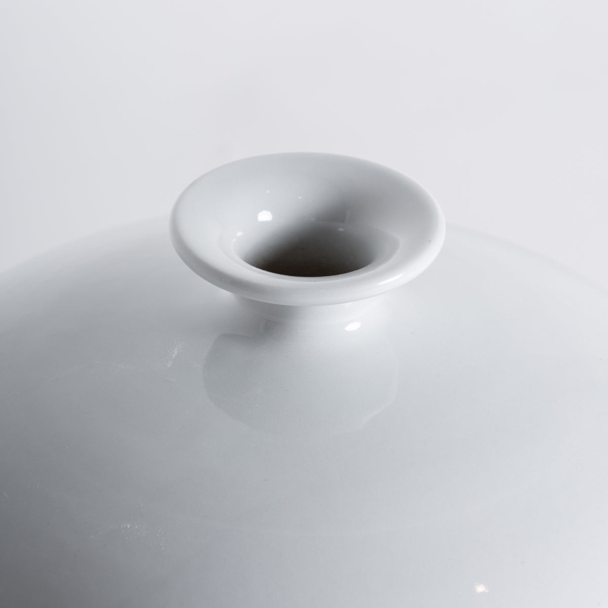 Primer plano de la abertura superior del Jarrón de cerámica blanca Jelen, con su acabado brillante sobre un fondo blanco liso, evocando un elegante estilo art déco.