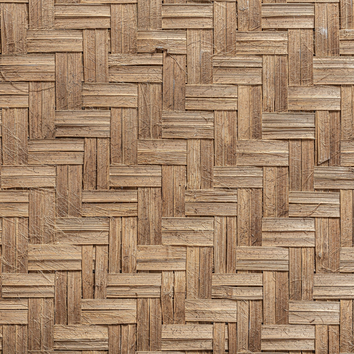 Primer plano del Panel decorativo en fibra natural león, con patrón de espiga tejida y tonos marrones tierra, ideal como panel decorativo para espacios de diseño boho.