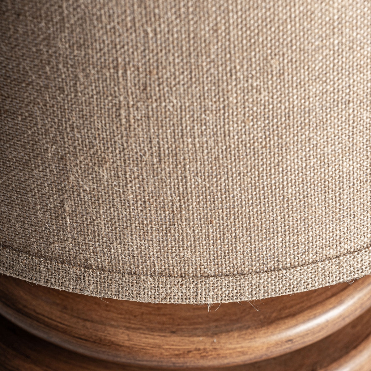Primer plano de la lámpara de sobremesa O-Deco, con pantalla de lino beige y base de resina, que captura la elegancia Art Deco con tela texturizada y acabado suave.