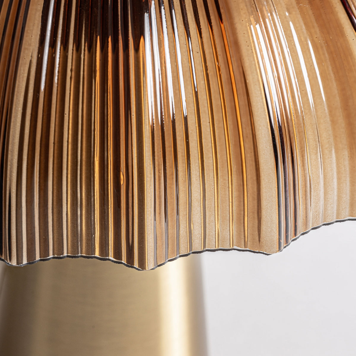 Primer plano de la Lámpara de mesa en cristal y acero MM70, que presenta un diseño metálico acanalado con borde festoneado que resalta sus superficies reflectantes y su textura detallada, aportando estilo y calidez a cualquier espacio.