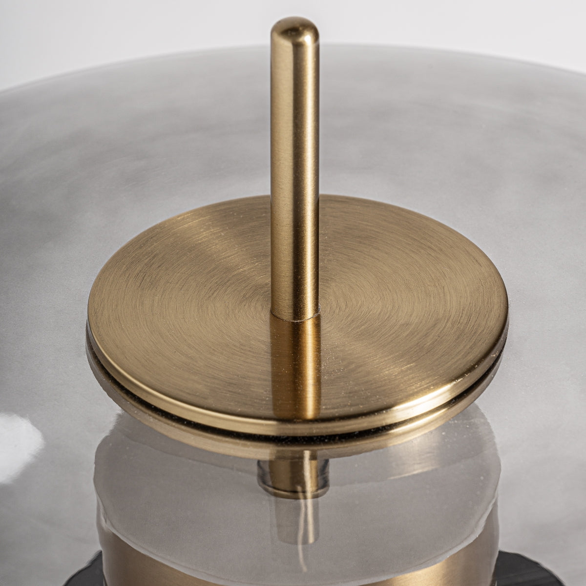 Primer plano del asa metálica dorada de la Lámpara de mesa en metal dorado y cristal ahumado Grau, unida a una tapa redonda de cristal ahumado, mostrando un elegante diseño art decó.