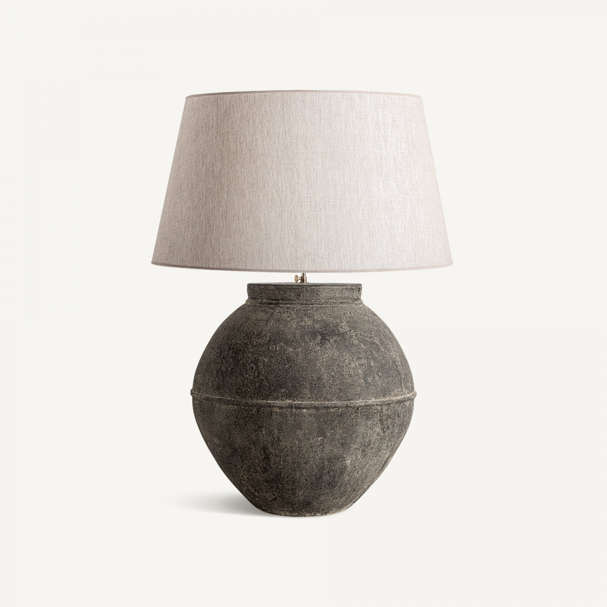 La lámpara de sobremesa en terracota y lino Mena, con base redonda en tono oscuro y pantalla clara, aporta elegancia atemporal y un sutil aire vintage sobre fondo blanco.