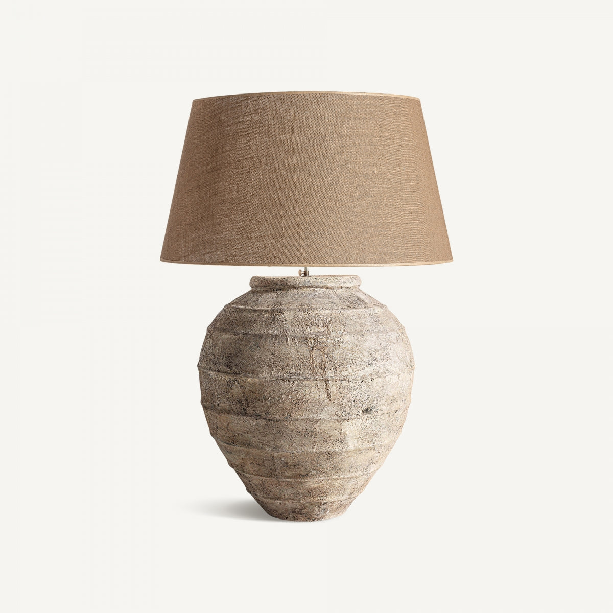 La Lámpara de mesa en cerámica y yute Provenzal B, con base texturizada de cerámica y pantalla beige de yute, aporta un toque sutil estilo provenzal sobre fondo liso.
