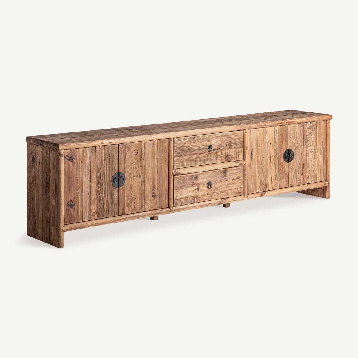 El Mueble TV de madera de pino reciclado Breive es un aparador largo de madera de pino reciclado con un acabado envejecido. Cuenta con dos armarios, dos cajones centrales y tiradores circulares de metal sobre un fondo liso.
