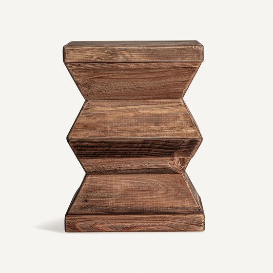 El taburete bajo Breive, elaborado a partir de madera reciclada con un acabado envejecido, presenta un diseño geométrico con bordes suaves y patrones de vetas de madera natural.