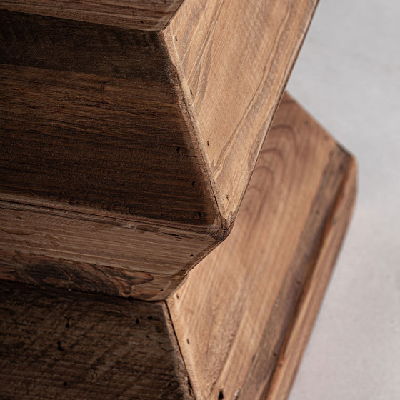 Primer plano del taburete bajo Breive de madera reciclada, con acabado envejecido y veta visible. Esta estructura geométrica con múltiples capas angulares es un ejemplo perfecto de diseño artesanal.