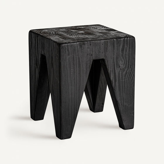 El Taburete bajo en madera reciclada negra Bruschal presenta un taburete de madera negra con un asiento cuadrado y patas geométricas sólidas, elaborado a partir de pino reciclado duradero para un diseño versátil.