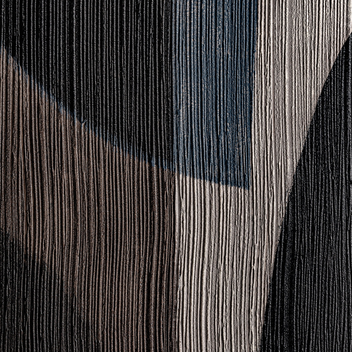 Primer plano del Cuadro contemporáneo en madera de pino negro (120x120 cm) Bobby que presenta una superficie texturizada con ranuras verticales y formas abstractas en negro, marrón, azul y blanco roto, ideal para decoración de interiores y amantes del arte contemporáneo.