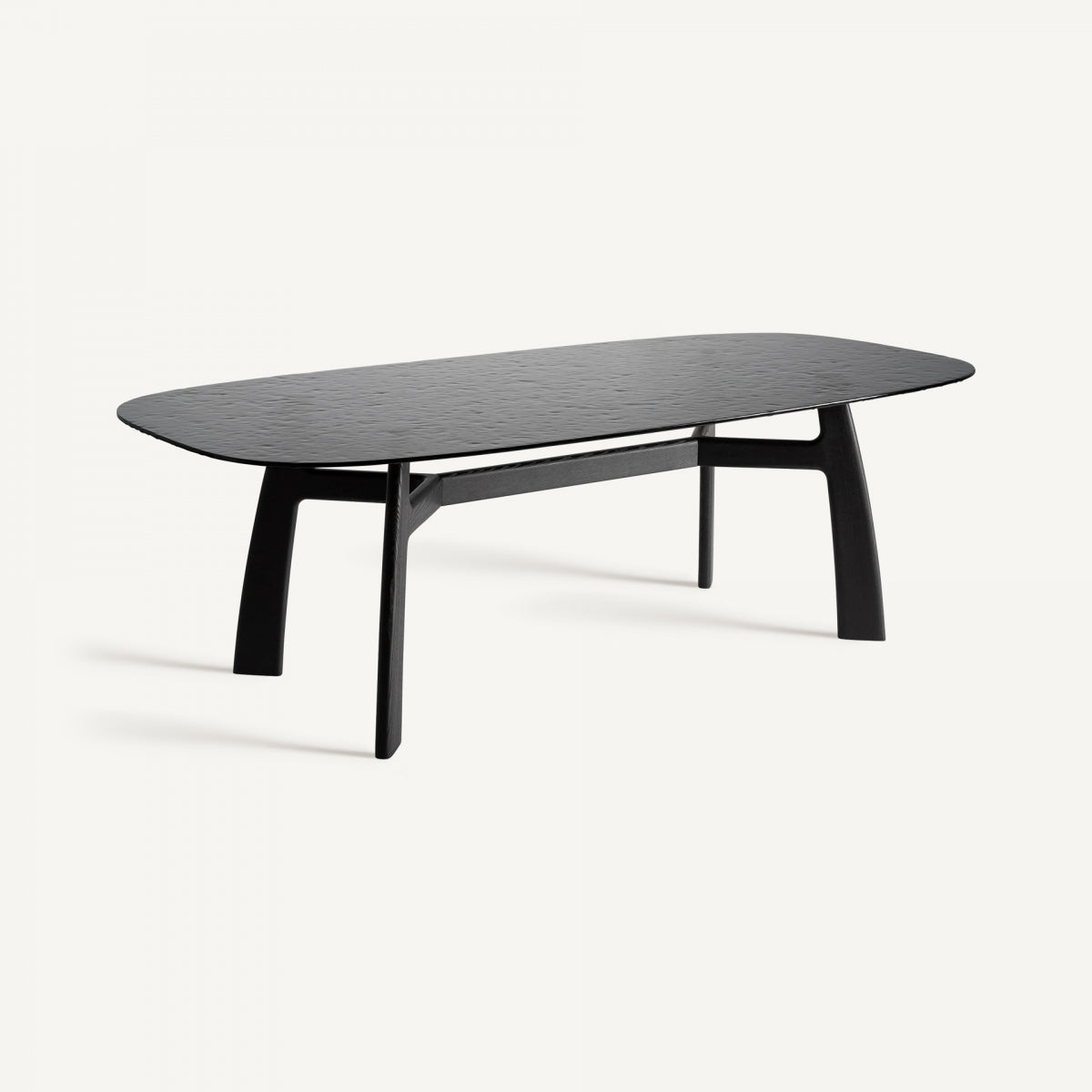 La mesa de comedor Suchdol presenta un diseño elegante y moderno con una tapa rectangular de vidrio templado y bordes redondeados, sostenida por cuatro patas en ángulo de madera de fresno negro.