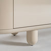 Primer plano de la esquina inferior de un mueble beige, redondeado, con patas cilíndricas sobre suelo liso, que recuerda al Mueble TV en madera DM gris Zorbig.