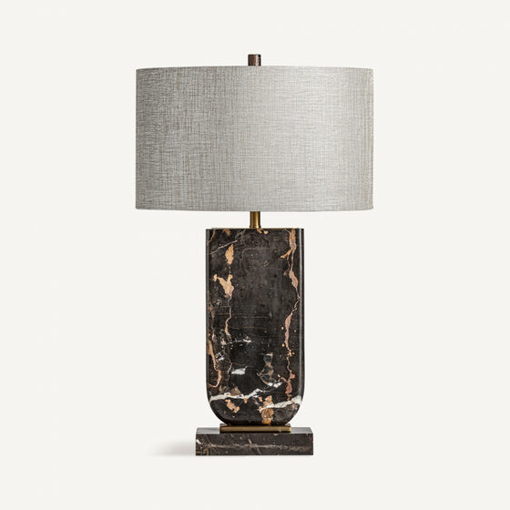Porta elegancia y estilo con la lámpara de mesa en mármol y metal Arty 83, que luce una base rectangular en mármol negro y dorado, y una gran pantalla cilíndrica gris sobre fondo blanco.