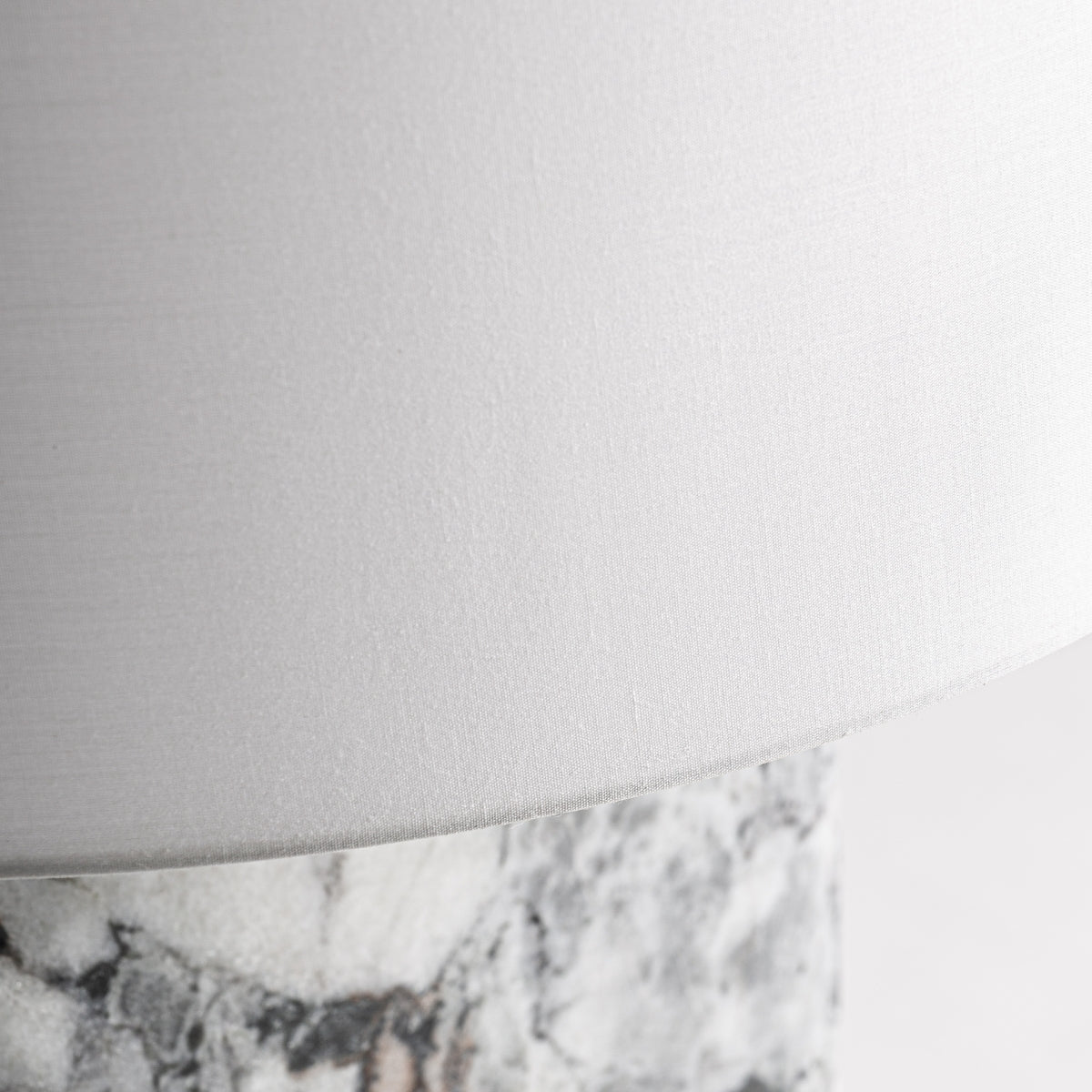 Primer plano de la Lámpara de mesa en mármol y metal Marble 84 con pantalla de tela blanca y base marmolada gris/mármol blanco, perfecta para interiores contemporáneos.