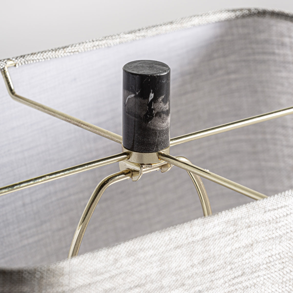 El primer plano de una pantalla con estructura metálica y remate negro irradia elegancia y sofisticación. Presenta una cubierta de tela cuadrada de color claro, ideal para la Lámpara de sobremesa en mármol negro y metal Ar-Deco.