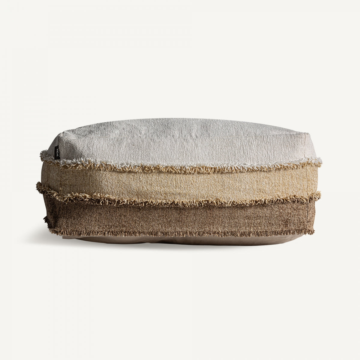 El Puff cuadrado en algodón y terciopelo Euken, un cojín rectangular de capas con tejido texturizado en tonos beige, marrón claro y marrón oscuro, bordes con flecos y un diseño elegante, se encuentra sobre un fondo blanco liso.