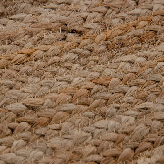 Un primer plano de la Alfombra en Yute Natural Circular Tierra muestra fibras de yute tejidas en un patrón trenzado, con tonos beige y marrón que encarnan la elegancia natural para la decoración del hogar.