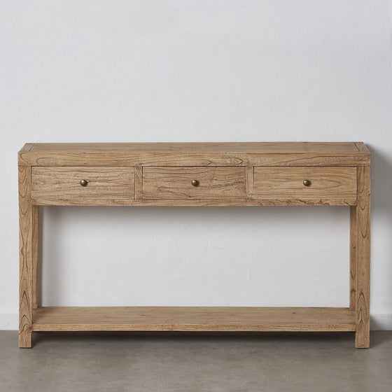 La Consola en Madera de Mindi Miró combina estilos modernos y rústicos con tres cajones y un estante inferior, elaborados en madera de mindi, colocados sobre una pared blanca.