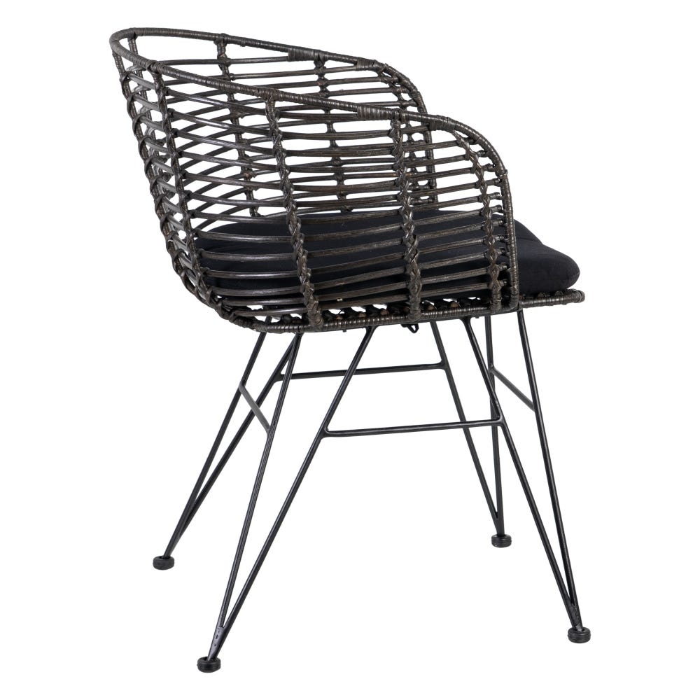 La Silla de Comedor en Ratán y Metal Nero presenta un diseño de ratán negro tejido, un elegante cojín y patas de metal resistentes, que encarnan un diseño moderno e industrial.