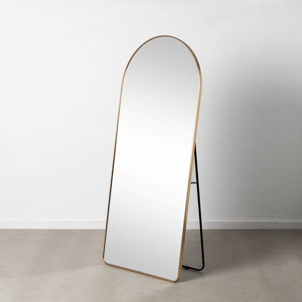 El Espejo de Aluminio Oro con Cristal Elegancia es un espejo de cuerpo entero independiente con una parte superior arqueada y un marco dorado delgado que muestra un diseño contemporáneo. Ubicado contra una pared blanca sobre un piso claro, personifica la elegancia del cristal.