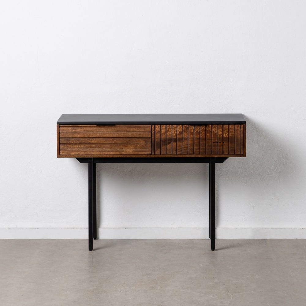 La Consola Marrón-Negro de Madera y Hierro Azen es una mesa consola moderna con una elegante tapa negra y un cajón de madera elaborado con madera de mango. Sus patas negras minimalistas aportan sofisticación industrial y ofrecen un contraste llamativo contra la pared blanca.