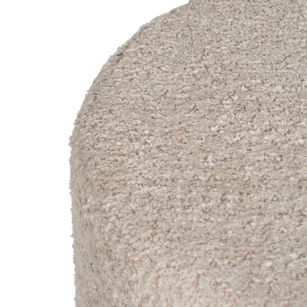 Primer plano de una tela texturizada de color beige claro con un borde ligeramente curvado, que recuerda los tonos suaves y el estilo acogedor que se encuentran en el Puf Redondo en Borreguito Cylia.