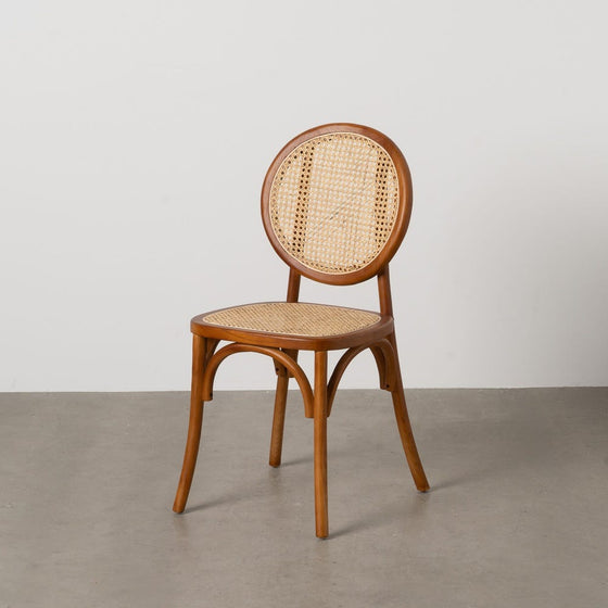 La Silla de comedor en Madera de Olmo Miel Edith, con un diseño clásico con respaldo y asiento de caña redondeados, está elegantemente colocada sobre un piso gris liso contra una pared blanca.